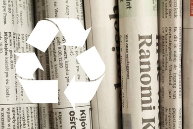 Image of Recycling symbol and many newspapers in different languages as background, closeup. Eco-friendly lifestyle, reusing
