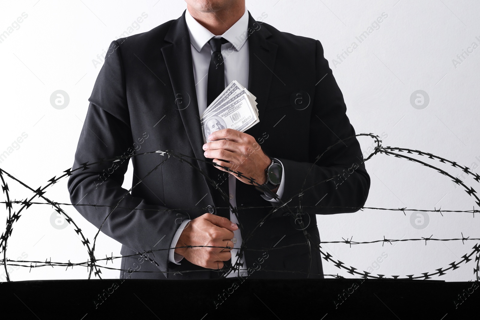 Stop corruption. Man with bribe behind metal barbed wire on light background, closeup Image of Stop corruption. Man with bribe behind metal barbed wire on light background, closeup