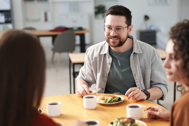 Photo of Colleagues chatting during lunch break in office