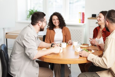 Photo of Colleagues chatting during lunch break in office