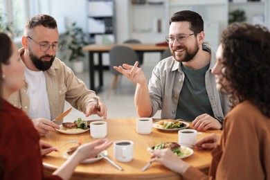 Photo of Colleagues chatting during lunch break in office