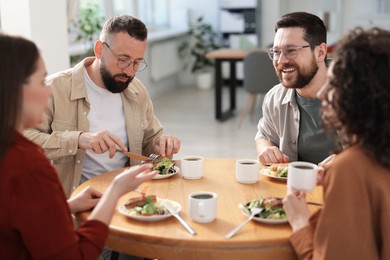 Photo of Colleagues chatting during lunch break in office