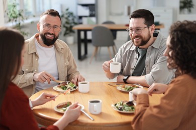Photo of Colleagues chatting during lunch break in office