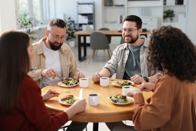 Photo of Colleagues chatting during lunch break in office