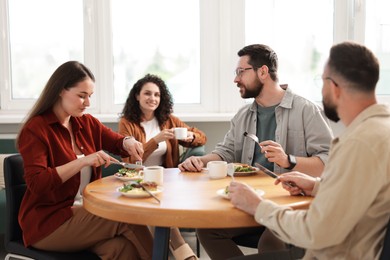 Photo of Colleagues chatting during lunch break in office