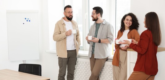 Photo of Colleagues chatting during coffee break in office
