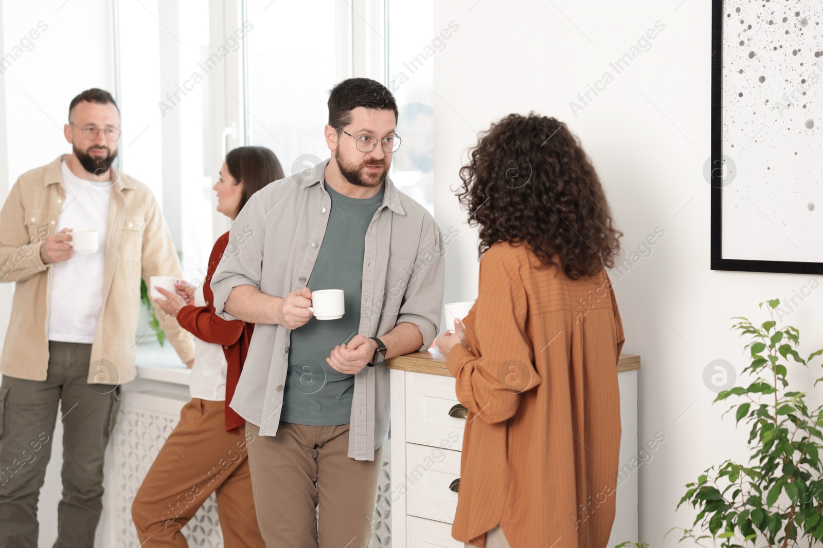 Colleagues chatting during coffee break in office Photo of Colleagues chatting during coffee break in office