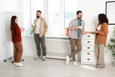 Photo of Colleagues chatting during coffee break in office