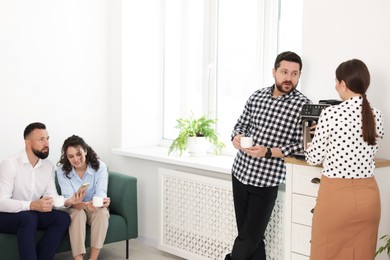 Photo of Colleagues chatting during coffee break in office. Space for text