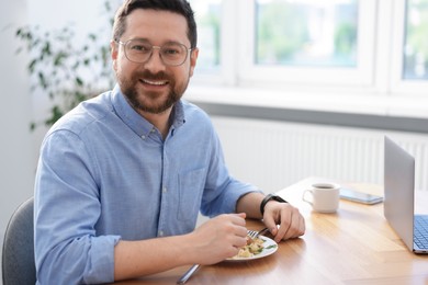 Photo of Man with meal at table during lunch break in office. Space for text