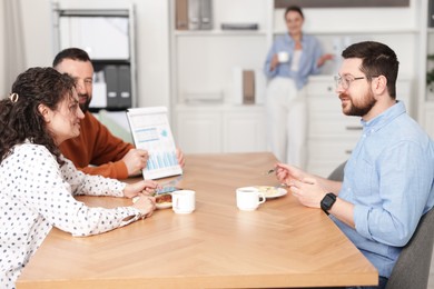 Photo of Colleagues eating and discussing work during lunch break in office