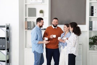 Photo of Colleagues chatting during coffee break in office