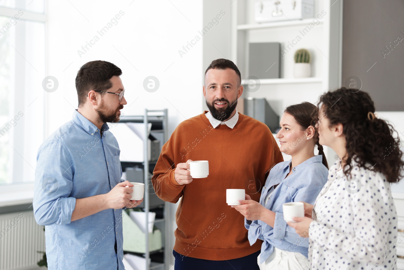 Colleagues chatting during coffee break in office Photo of Colleagues chatting during coffee break in office