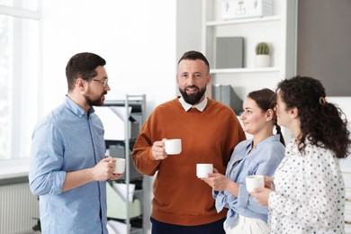 Photo of Colleagues chatting during coffee break in office