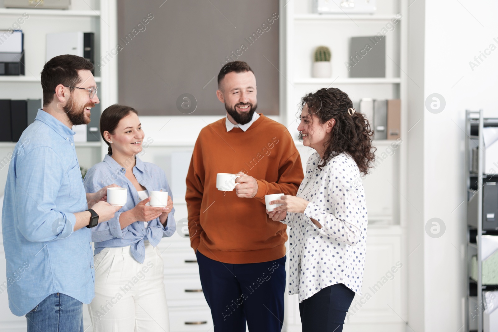 Colleagues chatting during coffee break in office Photo of Colleagues chatting during coffee break in office