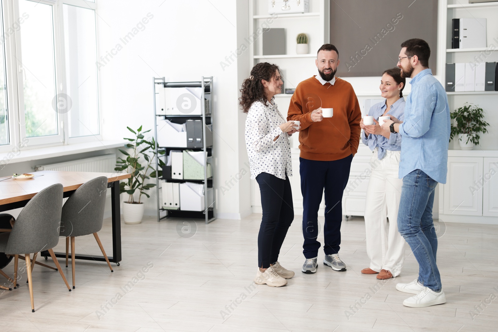Colleagues chatting during coffee break in office Photo of Colleagues chatting during coffee break in office