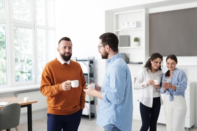 Photo of Colleagues chatting during coffee break in office
