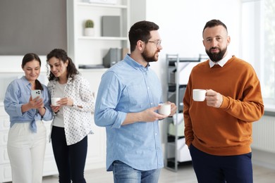 Photo of Colleagues chatting during coffee break in office