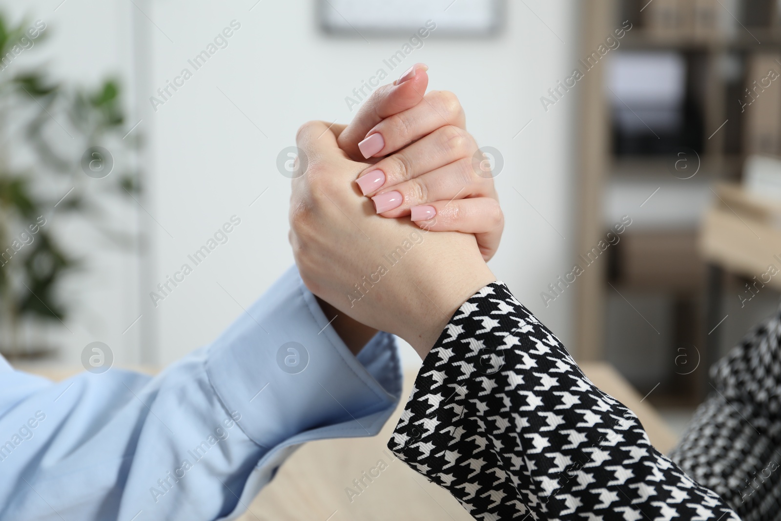 Businesswomen arm wrestling at table in office, closeup Photo of Businesswomen arm wrestling at table in office, closeup