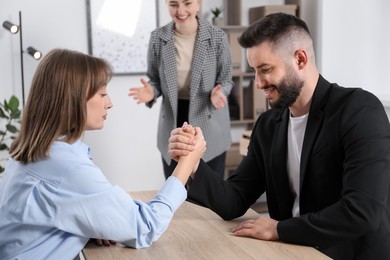 Photo of Businesspeople arm wrestling at wooden table in office, selective focus