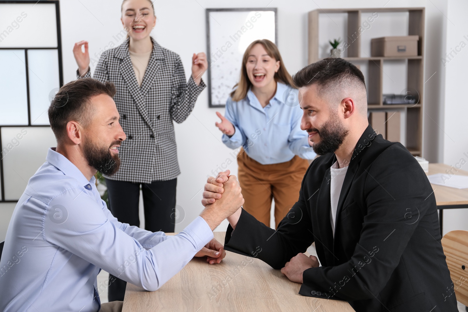 Businessmen arm wrestling at wooden table in office, selective focus Photo of Businessmen arm wrestling at wooden table in office, selective focus