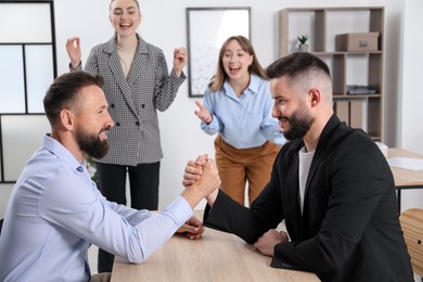 Photo of Businessmen arm wrestling at wooden table in office, selective focus