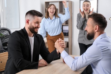 Photo of Businessmen arm wrestling at wooden table in office, selective focus