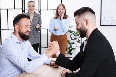 Photo of Businessmen arm wrestling at wooden table in office, selective focus