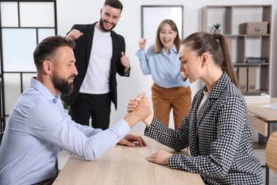 Photo of Businesspeople arm wrestling at wooden table in office, selective focus