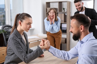 Photo of Businesspeople arm wrestling at wooden table in office, selective focus