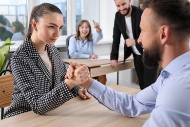 Photo of Businesspeople arm wrestling at wooden table in office, selective focus