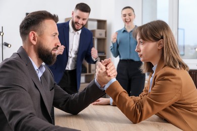 Photo of Businesspeople arm wrestling at wooden table in office, selective focus