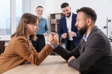 Photo of Businesspeople arm wrestling at wooden table in office, selective focus