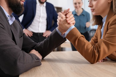 Photo of Businesspeople arm wrestling at wooden table in office, selective focus