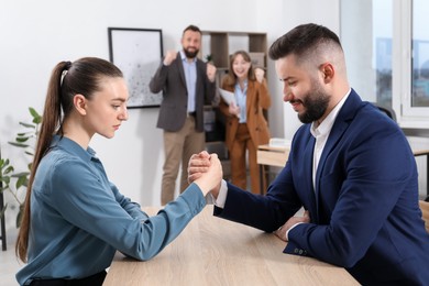 Photo of Businesspeople arm wrestling at wooden table in office, selective focus