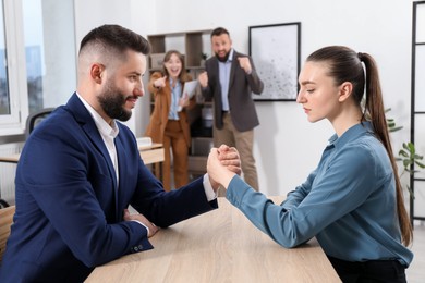 Photo of Businesspeople arm wrestling at wooden table in office, selective focus