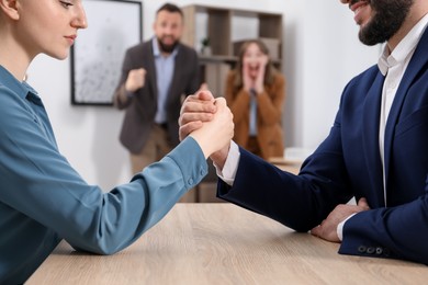 Photo of Businesspeople arm wrestling at wooden table in office, selective focus
