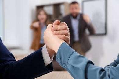 Photo of Businesspeople arm wrestling at table in office, selective focus