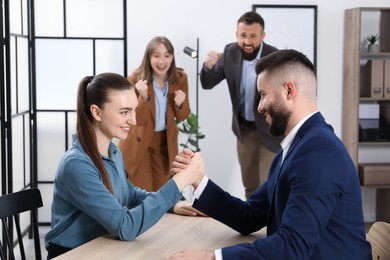 Photo of Businesspeople arm wrestling at wooden table in office, selective focus