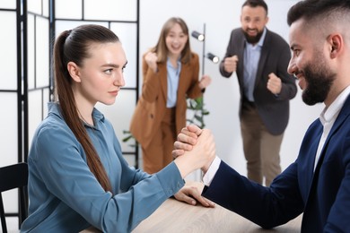 Photo of Businesspeople arm wrestling at wooden table in office, selective focus