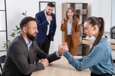 Photo of Businesspeople arm wrestling at wooden table in office, selective focus