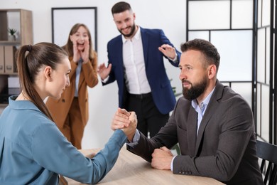 Photo of Businesspeople arm wrestling at wooden table in office, selective focus