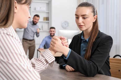 Photo of Businesswomen arm wrestling at wooden table in office, selective focus