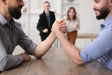 Photo of Businessmen arm wrestling at table in office, selective focus