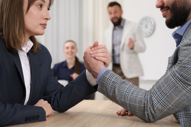 Photo of Businesspeople arm wrestling at wooden table in office, selective focus