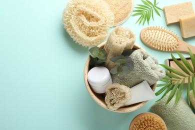 Photo of Flat lay composition with loofah sponges and floral decor on light blue background, space for text