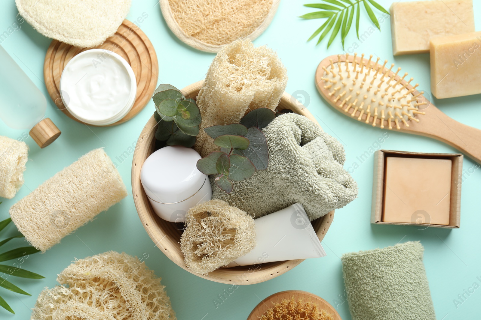Flat lay composition with loofah sponges and floral decor on light blue background Photo of Flat lay composition with loofah sponges and floral decor on light blue background