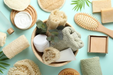 Photo of Flat lay composition with loofah sponges and floral decor on light blue background