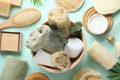 Photo of Flat lay composition with loofah sponges and floral decor on light blue background