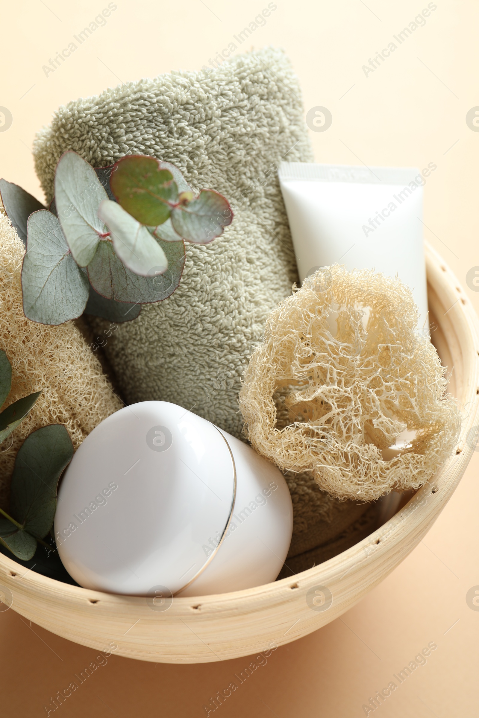 Loofah sponges, cosmetic products, towel and floral decor in bowl on beige background, above view Photo of Loofah sponges, cosmetic products, towel and floral decor in bowl on beige background, above view